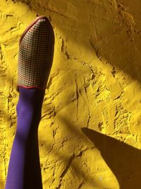 Midsection of woman standing against yellow wall