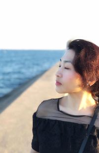 Woman standing at beach against sky