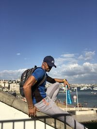 Side view of young man against blue sky