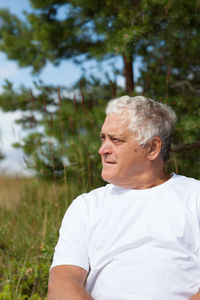 Mature man looking away while sitting on field