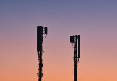 Low angle view of electricity pylon against clear sky during sunset