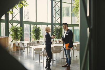 Business people talking while holding coffee cups at office cafeteria