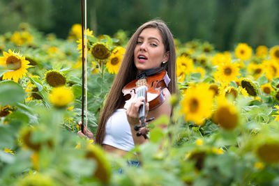 Portrait of woman with yellow flowers on field