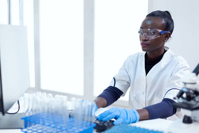 Portrait of scientist holding medicine while standing in laboratory