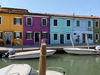 Boats moored in canal by buildings against clear sky