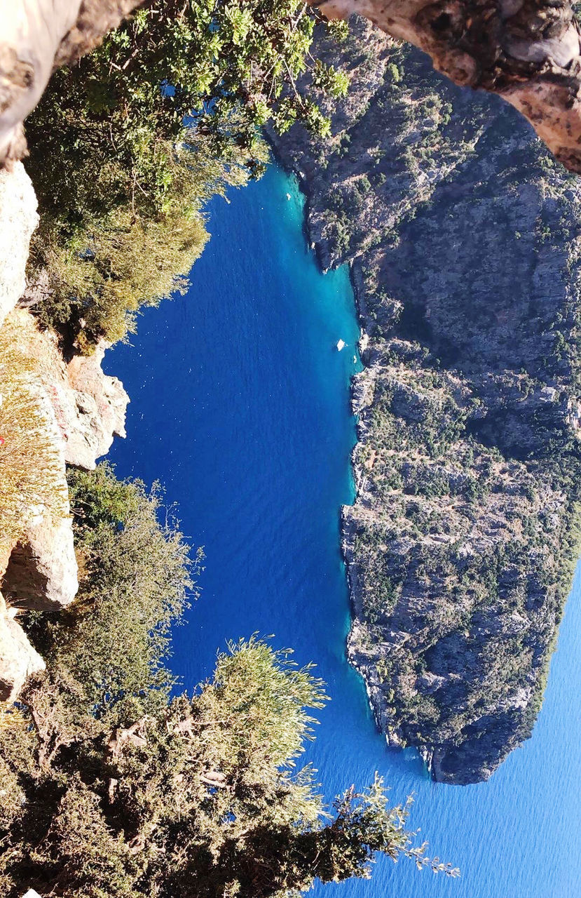 HIGH ANGLE VIEW OF ROCKS AND SEA AGAINST TREES