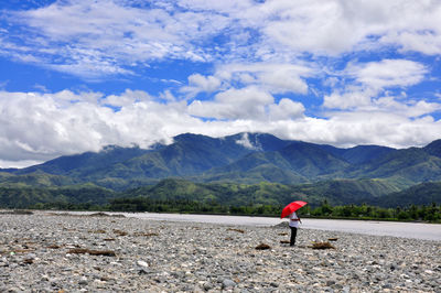 Man standing on mountain against cloudy sky