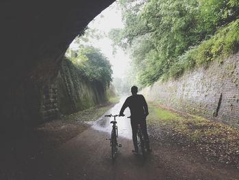 Rear view of man with bicycles in tunnel