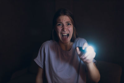 Portrait of young woman holding illuminated string lights