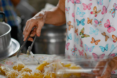 Midsection of person holding ice cream in kitchen