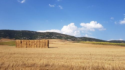 Hay bales on field against sky