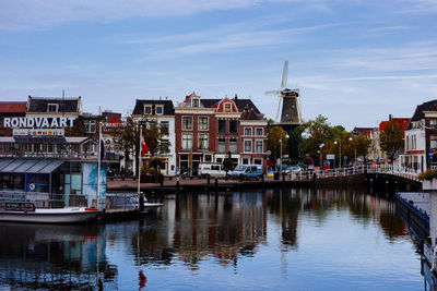 Boats moored on canal in city against sky