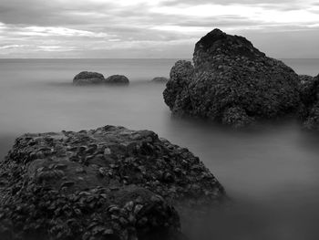 Rock formation in sea against sky