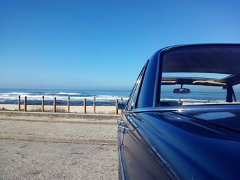 Close-up of car on beach against clear blue sky