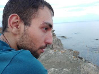 Portrait of young man on beach against sky