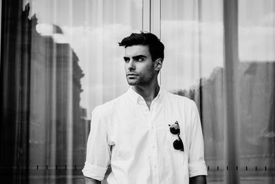 Handsome young man looking away while standing against building