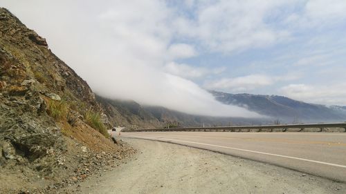 Empty road by mountains against sky