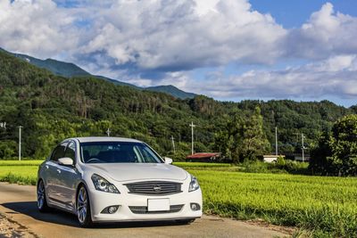 Car parked by mountains against cloudy sky