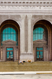 People resting on steps against historic building