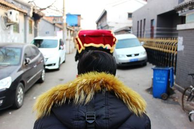 Rear view of person in fur coat on road