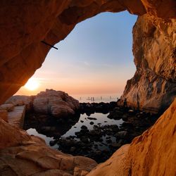 Rock formations by sea against sky during sunset