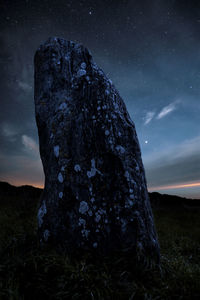 Rock formation on field against sky at night