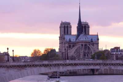 Bridge over river by notre dame de paris against cloudy sky