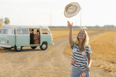 Happy young woman at camper van in rural landscape