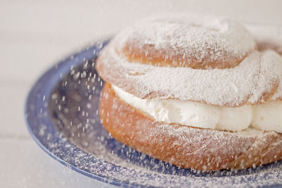 Cream puff filled with wipped sugar falling.