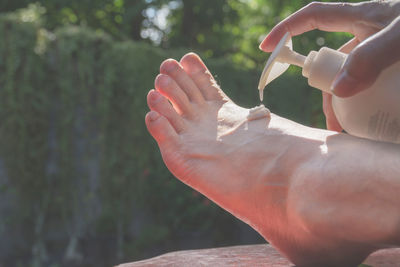 Low section of woman applying cream on leg