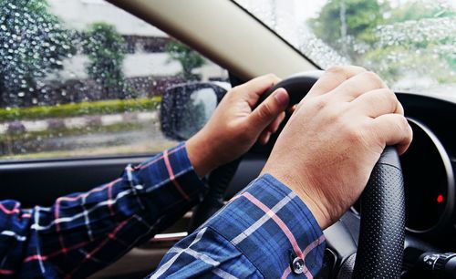 Midsection of man seen through car window