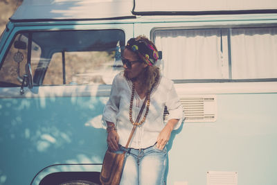 Rear view of young woman standing in car