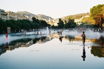 People on lake against clear sky