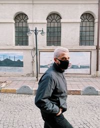 Full length of man standing on street against building