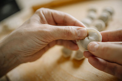Hands of woman molding dumpling in kitchen at home