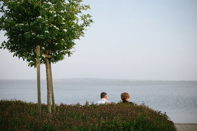 Rear view of couple on beach against sky