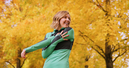 Young woman smiling while standing in park during autumn