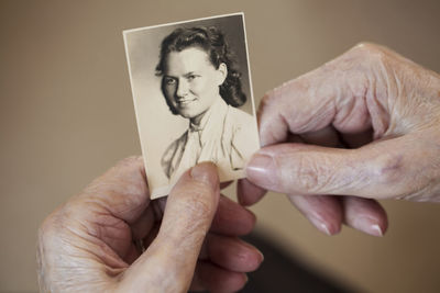 Hands of senior woman holding old photography of herself