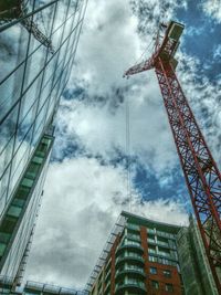 Low angle view of crane against cloudy sky