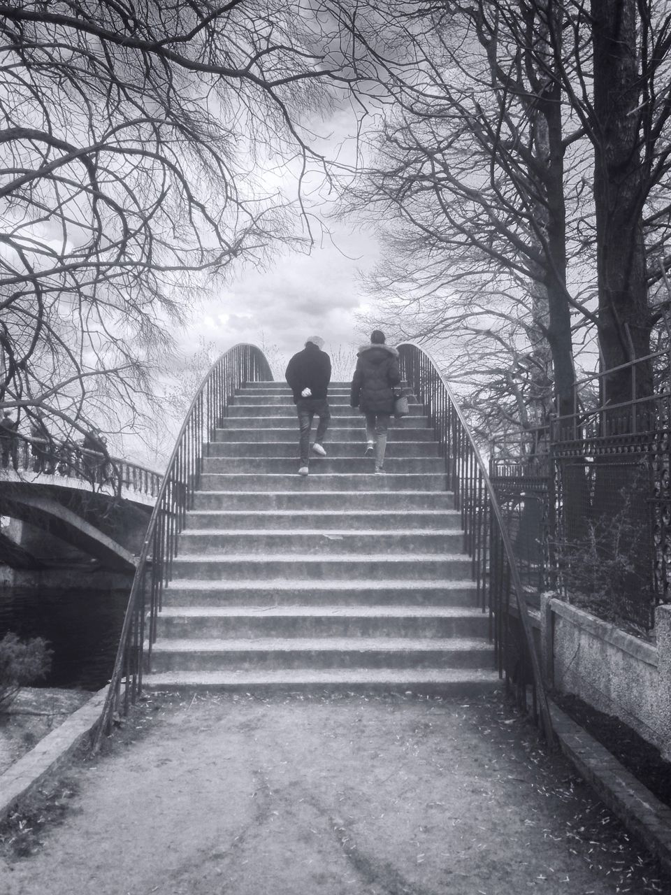 Rear view of man and woman moving up on steps at park