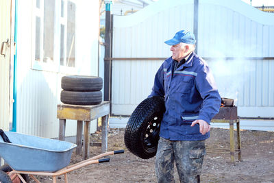 Old man washes a spare car wheel. change of winter wheels to summer ones.