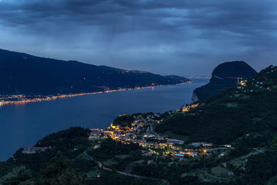 High angle view of illuminated city by sea against sky