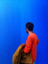 Rear view of man standing against blue background