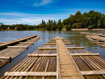 Wooden posts in lake against sky