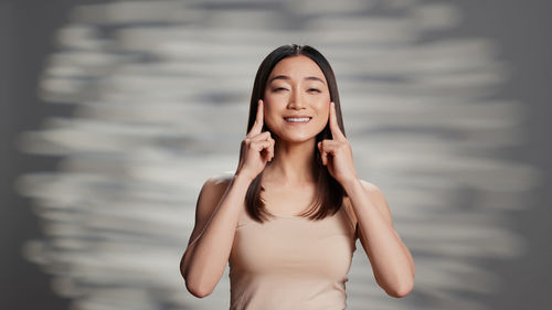 Portrait of young woman standing against sky