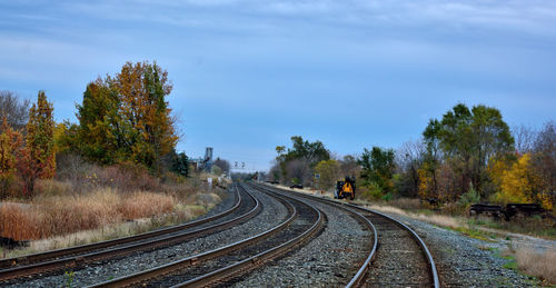 Railroad tracks amidst trees against sky during autumn