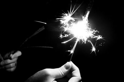 Person hand holding firework display at night
