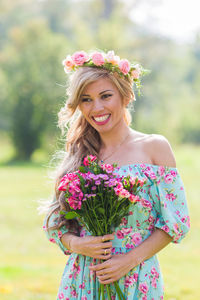 Portrait of happy woman standing against pink flower