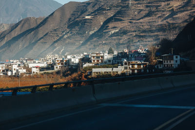 Road by buildings in city against sky