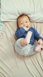 Portrait of smiling baby boy lying on bed at home